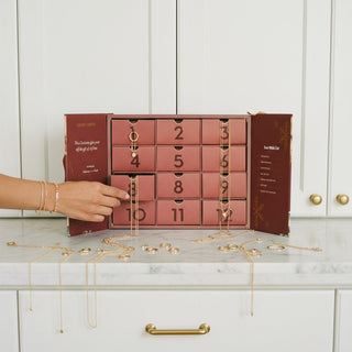 Advent calendar with numbered compartments on a countertop, filled with jewelry.